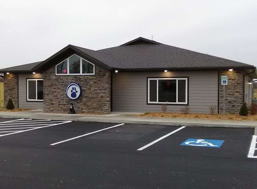 A single-story building featuring a stone facade, large windows, and a paw print logo on a circular sign.